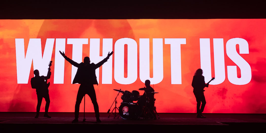 reference image for the band Black Paisley during the shooting of their music video at the Stockholm Fair. Large red and orange screen is visible in the background with the text Without us and the silhouettes of the band members in the foreground.