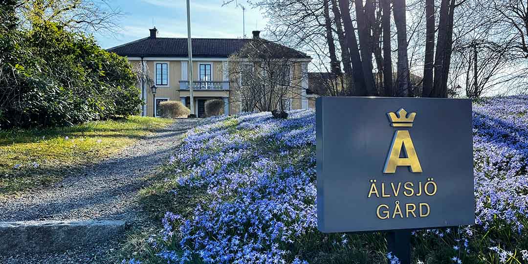 the picture shows älvsjö gård mansion in spring with purple flowers.