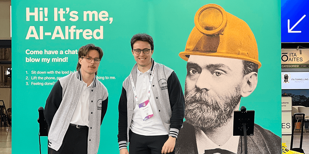 Two student hosts from local Stockholm universities in front of a wall with Alfred Nobel during the World Tunnel Congress 2025 at Stockholmsmässan.